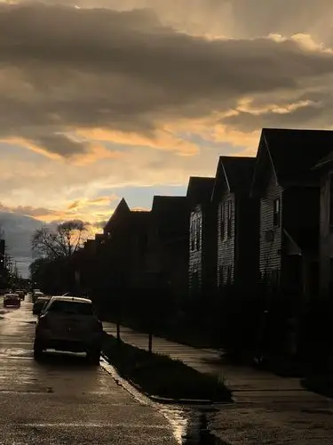 Twilight paints dramatic clouds above a wet, reflective street.